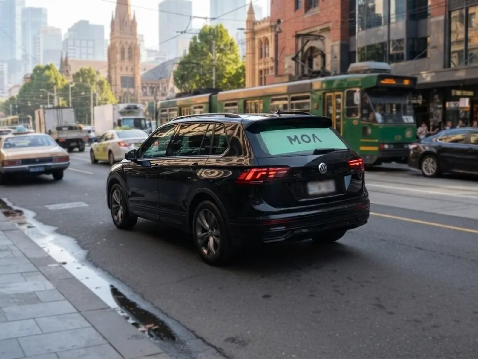 MOA branded SUV in Melbourne city traffic, rear window ad visible to the cars behind