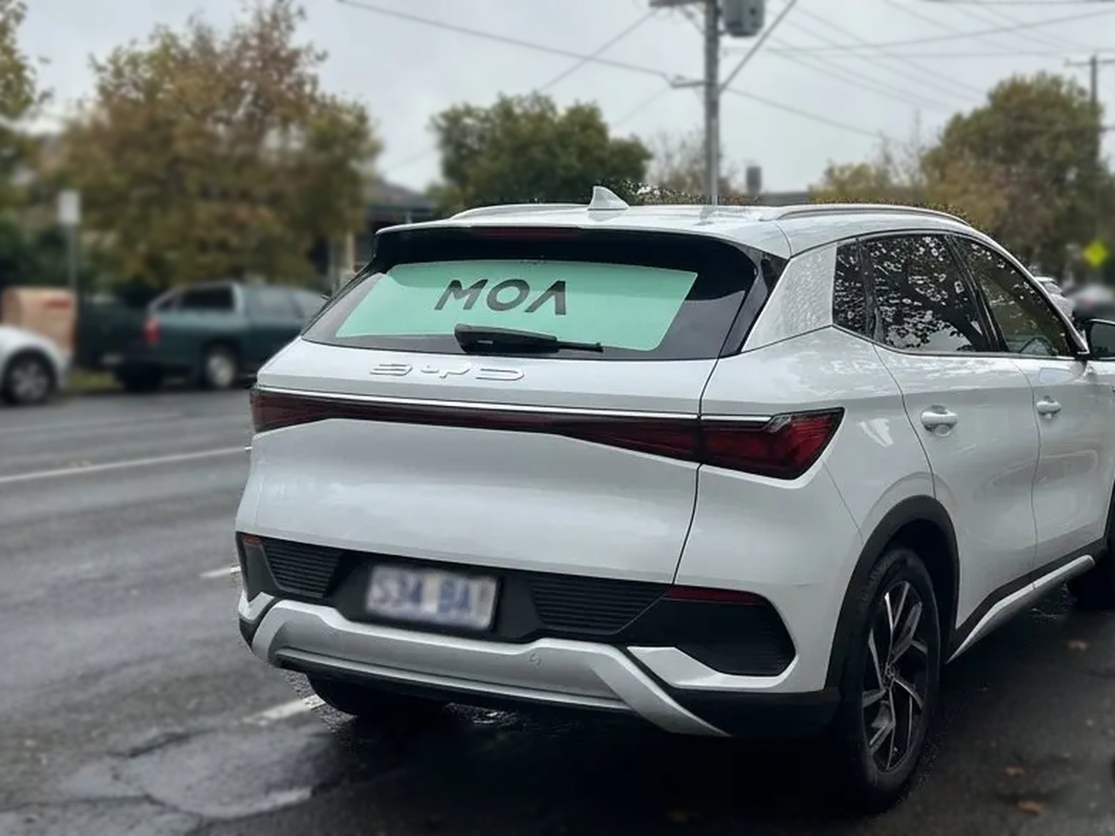 MOA branded white SUV on a residential street lined with autumn trees
